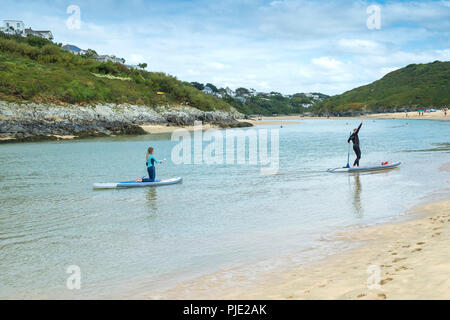 Urlauber auf Stand up Paddleboards auf dem Fluss Gannel an Crantock Beach in Newquay Cornwall. Stockfoto