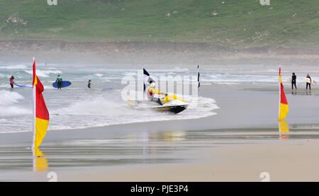 RNLI Rettungsschwimmer nähert sich der Strand auf Rettung Jet Ski, Sennen Cove, Cornwall, England, Großbritannien Stockfoto