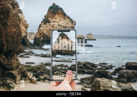 Ein Tourist an der Atlantikküste in Portugal nimmt Bilder von der schönen Aussicht auf das Meer und die Felsen. Erstaunlich natürliche Landschaft. Stockfoto