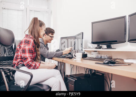 Bild der glücklichen jungen Kolleginnen und Kollegen im Büro, Arbeiten am Projekt und die Verwendung von Desktop-pcs Stockfoto