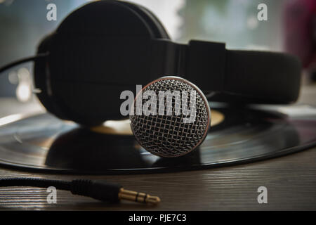 Mikrofon und Kopfhörer auf alten Vinyl-Schallplatte. Musik, Gesang, DJ, Club oder Vintage record Konzept Stockfoto