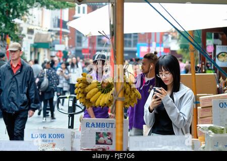 Junge chinesische Frau mit Handy in Chinatown markt Gerrad Street London England Großbritannien Stockfoto