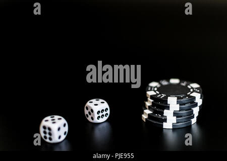 Würfel und monochrome Casino Chips auf schwarzem Hintergrund. Stockfoto