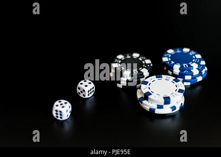 Würfel und farbigen Casino Chips auf einem schwarzen Hintergrund. Stockfoto