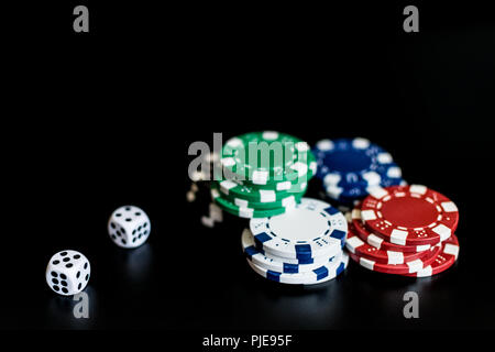 Würfel und farbigen Casino Chips auf einem schwarzen Hintergrund. Stockfoto