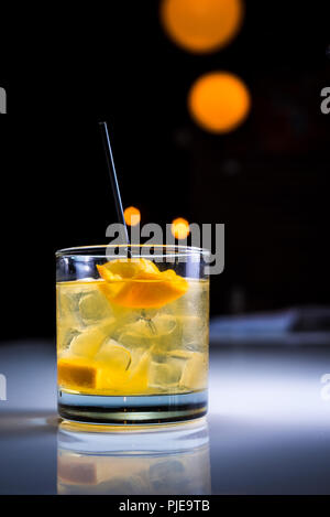 Ein Handwerk Cocktail mit orangen Garnitur in ein Glas mit Eiswürfeln auf schwarzem Hintergrund Stockfoto