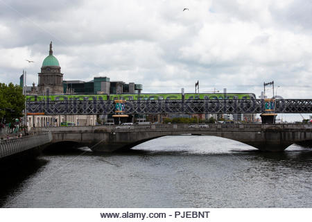 Eine grüne DART Zug überquert den Fluss Liffey in Dublin an einem hellen Sommer. Stockfoto