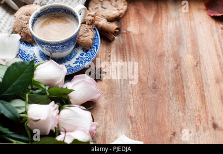 Romantische Kaffee in einer Tasse auf einem hölzernen Hintergrund mit einem Plaid, ein Blumenstrauß aus den weißen Rosen und im Herbst Gemütlichkeit. Guten Morgen. obere Ansicht. Kopieren Sie spase Stockfoto
