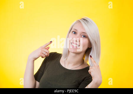 Selbstbewusst und Stolz lächelnde junge Frau mit Händen zu sich hin. Glücklich über bunte gelben Hintergrund isoliert aufgeregt. Stockfoto