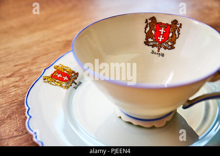 Sehr alte vintage Cup mit einer Platte auf einen hölzernen Tisch, beide mit 'Danzig' unter dem Wappen der Stadt zeigt zwei Löwen in Gold geschrieben und Stockfoto