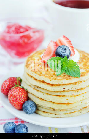 Einen Stapel Pfannkuchen mit reifen Himbeeren, Heidelbeeren und saure Sahne in der Nähe eingerichtet - bis Stockfoto