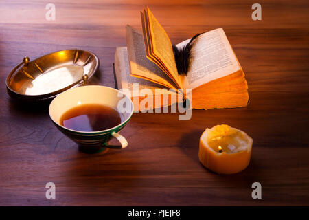 Ein offenes Buch auf dem Tisch. Ein düsteres brennende Kerze. Stockfoto