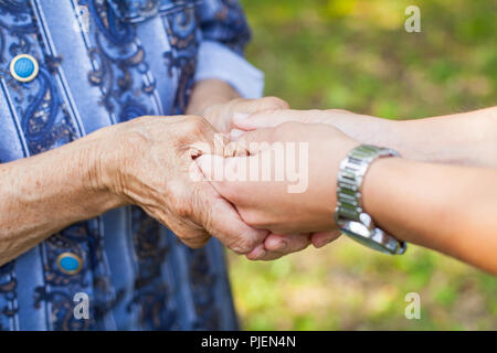 Nahaufnahme Bild der jungen Frau, die faltige Hand ihrer älteren Großmutter Holding Stockfoto