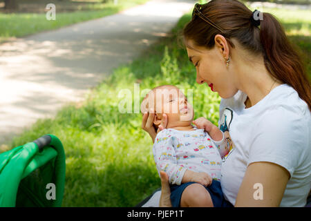 Mutter und Kind, glückliche junge Frau, die ihre niedlichen Baby in den Händen halten, liebevolle Mutter lächelnd und Kuscheln auf Ihrem kleinen Neugeborenen, Mutterschaft Liebe Stockfoto