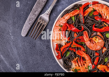 Schwarze Spaghetti mit Garnelen und Gemüse, Ansicht von oben. Stockfoto