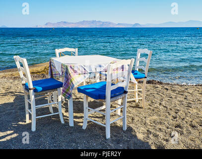 Ein Tisch mit Stühlen, eine griechische Taverne in der Nähe des Meeres in einem Strand der Insel Kos, Griechenland. Stockfoto