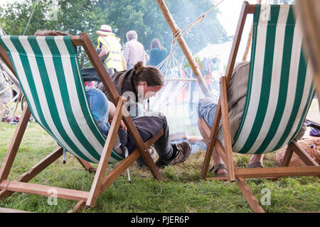 Newport, Wales - 23 Aug 16: Sitzen auf Liegestühlen neben dem Feuer beobachten das Festival gehen am 16. August 2015 Im Green Gathering Festival Stockfoto