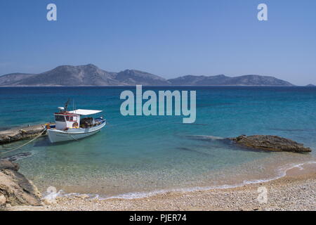 Griechenland, die wunderschöne Insel Koufonissi. Ein kleines Fischerboot ist an einem kleinen Steg an einem Strand vertäut. In der Ferne befindet sich die Insel Keros. Stockfoto