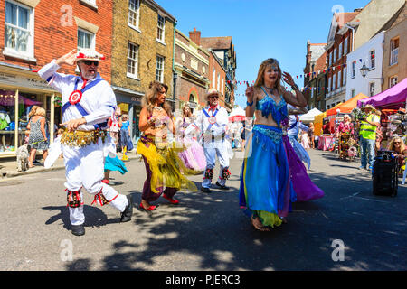 Reife Frauen von Bauchtanz Gruppe der "guten Karma Damen führen Sie mit einigen lokalen Morris Dancers in einer Straße in der Stadt Sandwich, Kent. Stockfoto