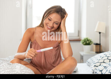 Junge Frau wegen der Schwangerschaft Test führen. Frau mit einem Schwangerschaftstest in der Hand Stockfoto