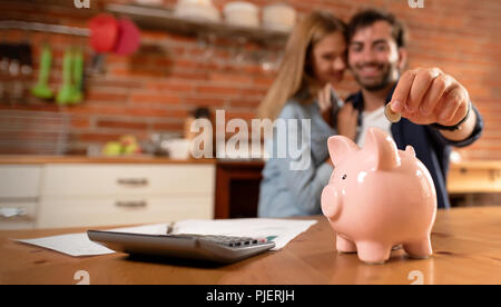 Glückliches Paar einfügen Münze im Sparschwein. Home Haushalt, Familie Finanzen Konzept. Foto breit mit Platz für Ihren Text Stockfoto