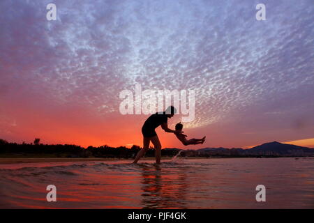 Yantai, China Provinz Shandong. 5. Sep 2018. Vater und Tochter spielen im Sonnenuntergang am Meer, in der Stadt Yantai, Provinz Shandong im Osten Chinas, Sept. 5, 2018. Credit: Tang Ke/Xinhua/Alamy leben Nachrichten Stockfoto