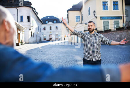 Ein erwachsener hipster Sohn und seinem Vater in der Stadt, Gruß. Stockfoto