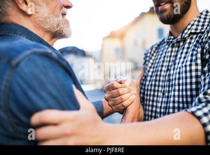 Nicht erkennbare Sohn und seine überglücklich senior Vater in der Stadt, Gruß. Stockfoto