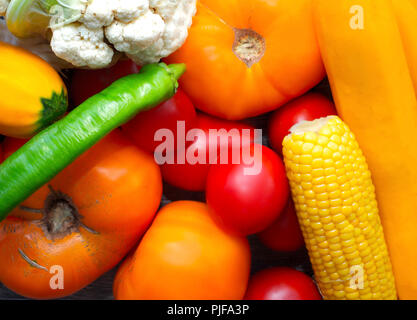 Buntes Gemüse Hintergrund. Reife cognac Gemüse close-up auf den Tisch. Tomaten, Blumenkohl, Zucchini, Mais, Paprika und Kräuter Stockfoto