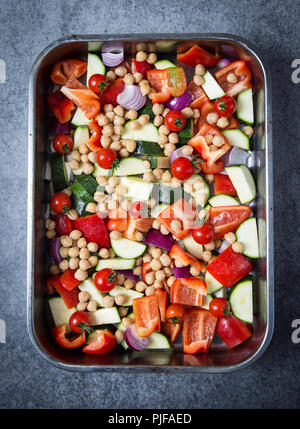 Ein Gemüse medley bestehend aus gehackten rohen Paprika, Zucchini, rote Zwiebeln und Tomaten mit gekochten Kichererbsen, fertig gebacken, die sich in der o zu sein Stockfoto