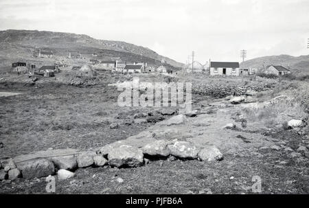 1950, historische, kleine Siedlung auf den Äußeren Hebriden, Western Isles, Schottland, UK, zeigt die karge, steinige Landschaft anda Paar kleine single-store crofters Hütten thront auf dem Hügel. Stockfoto