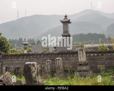 Friedhof mit Grabsteinen, Masten auf die Skyline ridge, nebligen Tag, Landschaft, Ehime, Shikoku, Japan Stockfoto