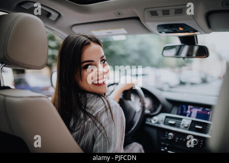 Zurück Blick auf ein attraktives Geschäft Frau suchen über ihre Schulter, während das Auto fahren Stockfoto