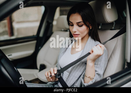 Elegante Frau auf Sicherheitsgurt in Ihrem Auto Stockfoto