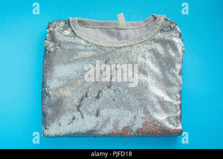 Elegante Damen sweatshirt liegt auf einem blauen Hintergrund der Ansicht von oben. Glänzende Textur Dekor pailletten Mode Stockfoto