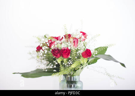 Vase mit schönen Blumen, roten Rosen und grünen Blättern auf weißem Hintergrund Danke und Card Design Zimmer für text Liebe Stockfoto