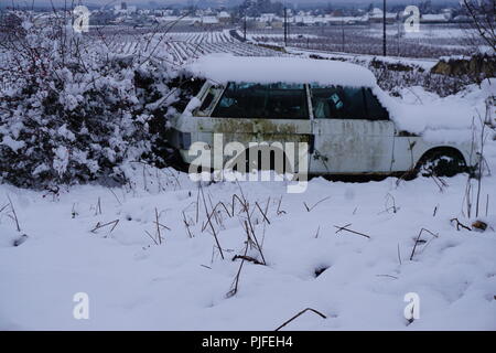 Eine zerstörte verlassenen alten rostigen Auto in dem Land an einem stürmischen verschneiten Tag im Tal der Loire, Frankreich Stockfoto