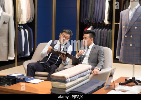 Fashion Designer und Kunden im Gespräch in Herrenmode shop Stockfoto