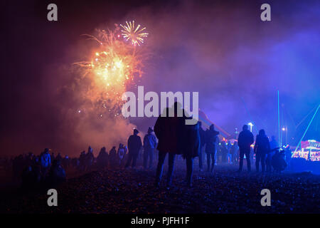 Ein paar Hug am Strand wie Sie beobachten Feuerwerk explodieren über ihren Köpfen in den Nachthimmel auf Lagerfeuer Nacht, Feuerwerk Nacht in Petworth Stockfoto