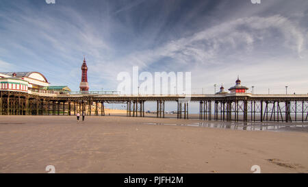 Blackpool, England, Großbritannien - 1 August 2015: Ein paar Spaziergang auf dem Sand Strand von Blackpool unterhalb der berühmten Blackpool Tower und Blackpool North Pier. Stockfoto