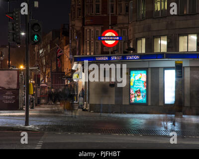 London, England, UK - 27. Februar 2018: Fußgänger entlang der Tottenham Court Road außerhalb der Londoner U-Bahnstation Warren Street bei Nacht. Stockfoto