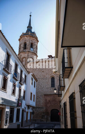 Tembleque, Spanien, ist ein kleines Dorf mit einer Kirche und einem Uhrenturm im Zentrum, das an einem Sommertag ohne Wolken am Himmel fotografiert wurde. Stockfoto