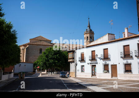 Tembleque, Spanien, ist ein kleines Dorf mit einer Kirche und einem Uhrenturm im Zentrum, das an einem Sommertag ohne Wolken am Himmel fotografiert wurde. Stockfoto