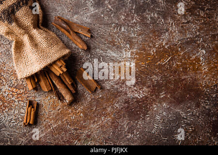Zimtstangen in einem Canvas Tasche auf grunge braunen Hintergrund Stockfoto