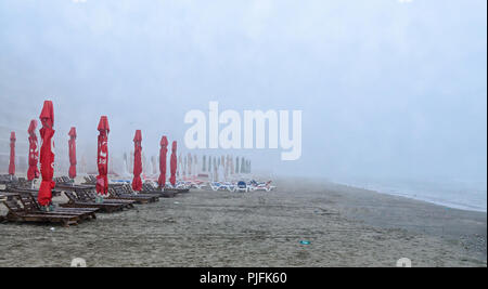 MAMAIA, Rumänien - 15. SEPTEMBER 2017: Strand des Schwarzen Meeres von Mamaia, Rumänien mit Sonnenliegen und Sonnenschirmen, nebligen Tag. Stockfoto