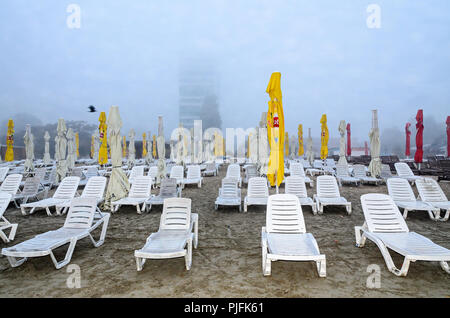 MAMAIA, Rumänien - 15. SEPTEMBER 2017: Strand des Schwarzen Meeres von Mamaia, Rumänien mit Sonnenliegen und Sonnenschirmen, nebligen Tag. Stockfoto