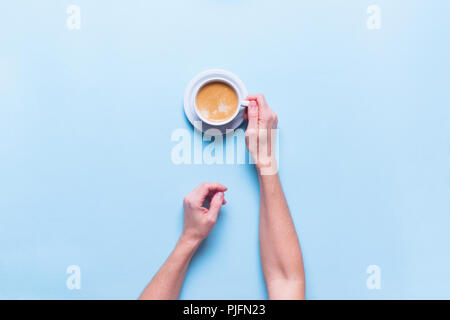 Weibliche Hände hält frische Tasse Kaffee Farbe blau Hintergrund der Ansicht von oben Flach ungesunde Nahrung ein Objekt Stockfoto