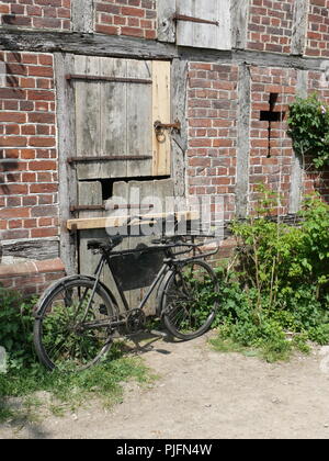 Altes Fahrrad hielten gegen eine alte hölzerne Tür, Suffolk, England Stockfoto