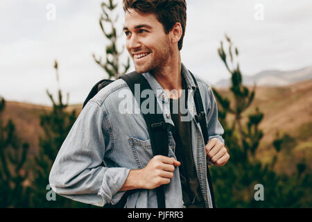 Menschen auf dem Weg durch einen Wald trägt eine Jacke und Rucksack. Glückliche Menschen auf einem Urlaub Wandern in ländlicher Umgebung. Stockfoto