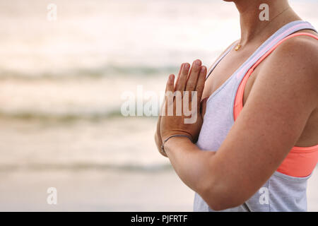 Nahaufnahme einer Frau mit Palmen Yoga am Strand. Seitenansicht einer Frau üben Meditation, der am Ufer des Meeres. Stockfoto